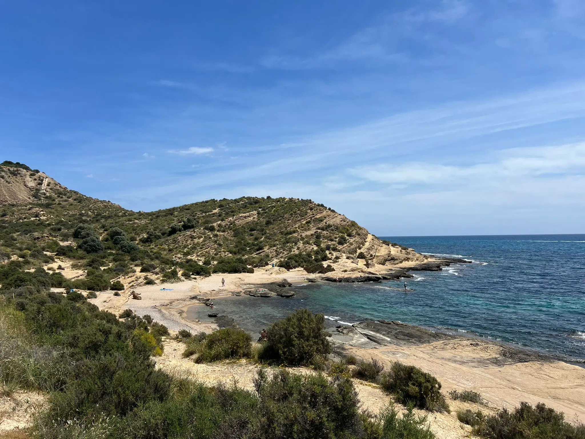 Cala Cantalar Alicante — full panoramic view of the secluded rocky cove at Cabo de las Huertas with turquoise water, natural vegetation and few visitors on the beach
