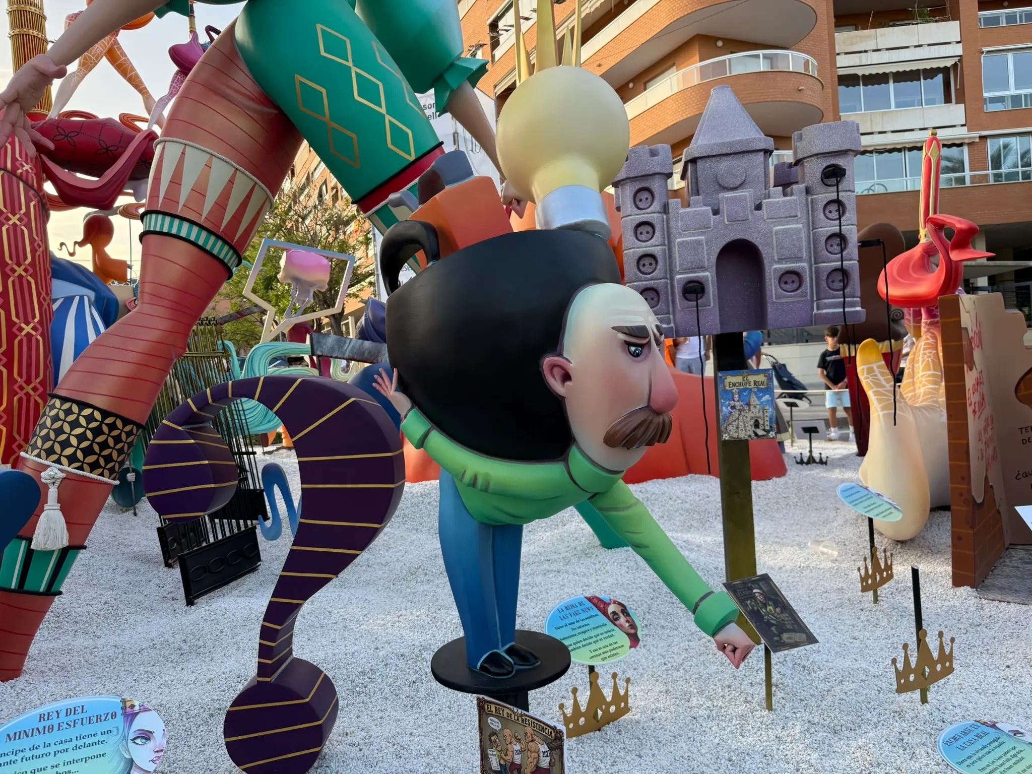Detailed close-up of a satirical Fogueres figure made of papier-mâché and wood, displayed on an Alicante street during the Hogueras de San Juan festival