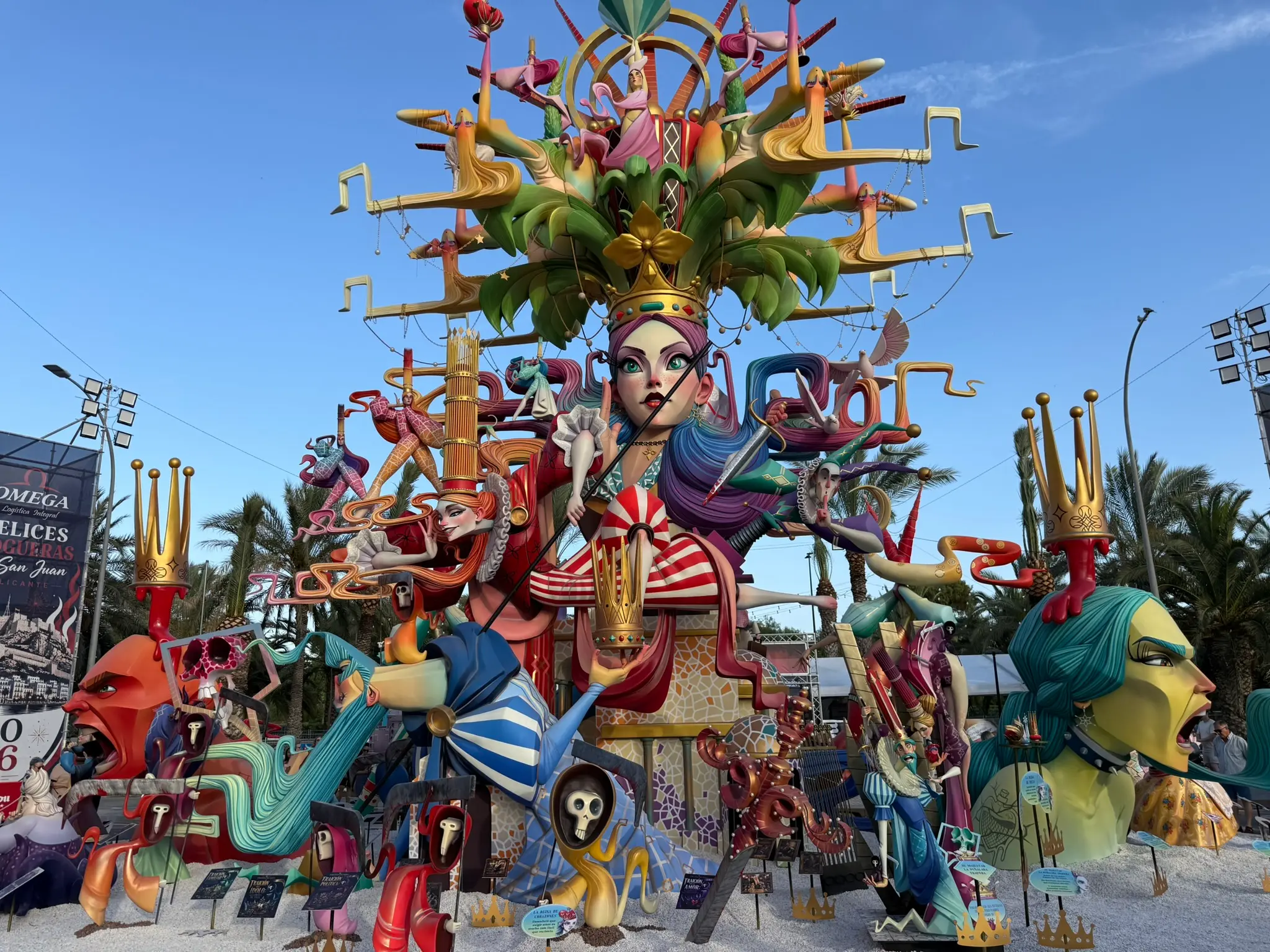 Detailed close-up of a grand, multi-tiered Hogueras monument showcasing intricate papier-mâché sculptures, historical characters, and colorful branching elements with star lanterns