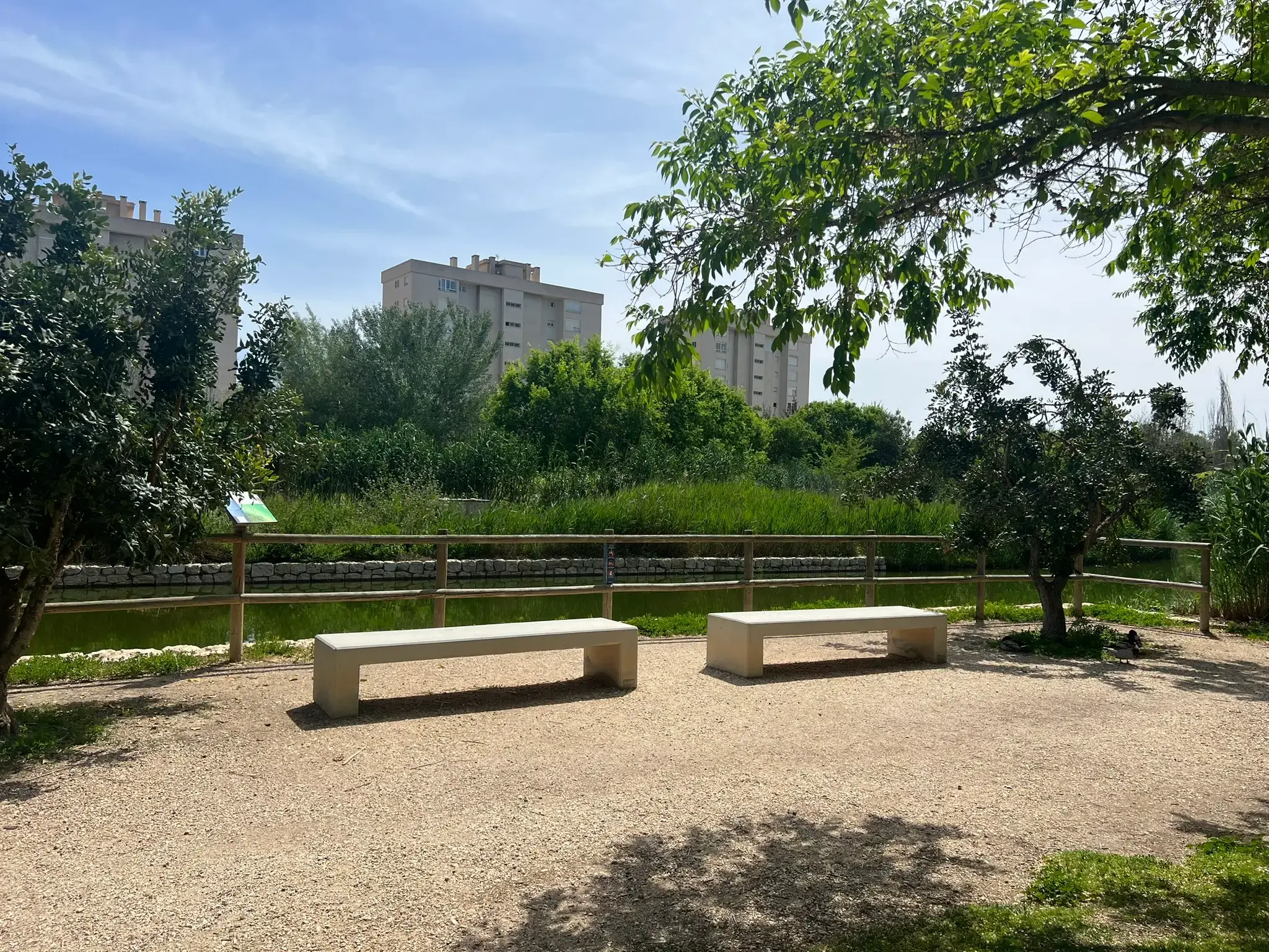 Shaded lakeside resting area with seating at Parque La Marjal Alicante.