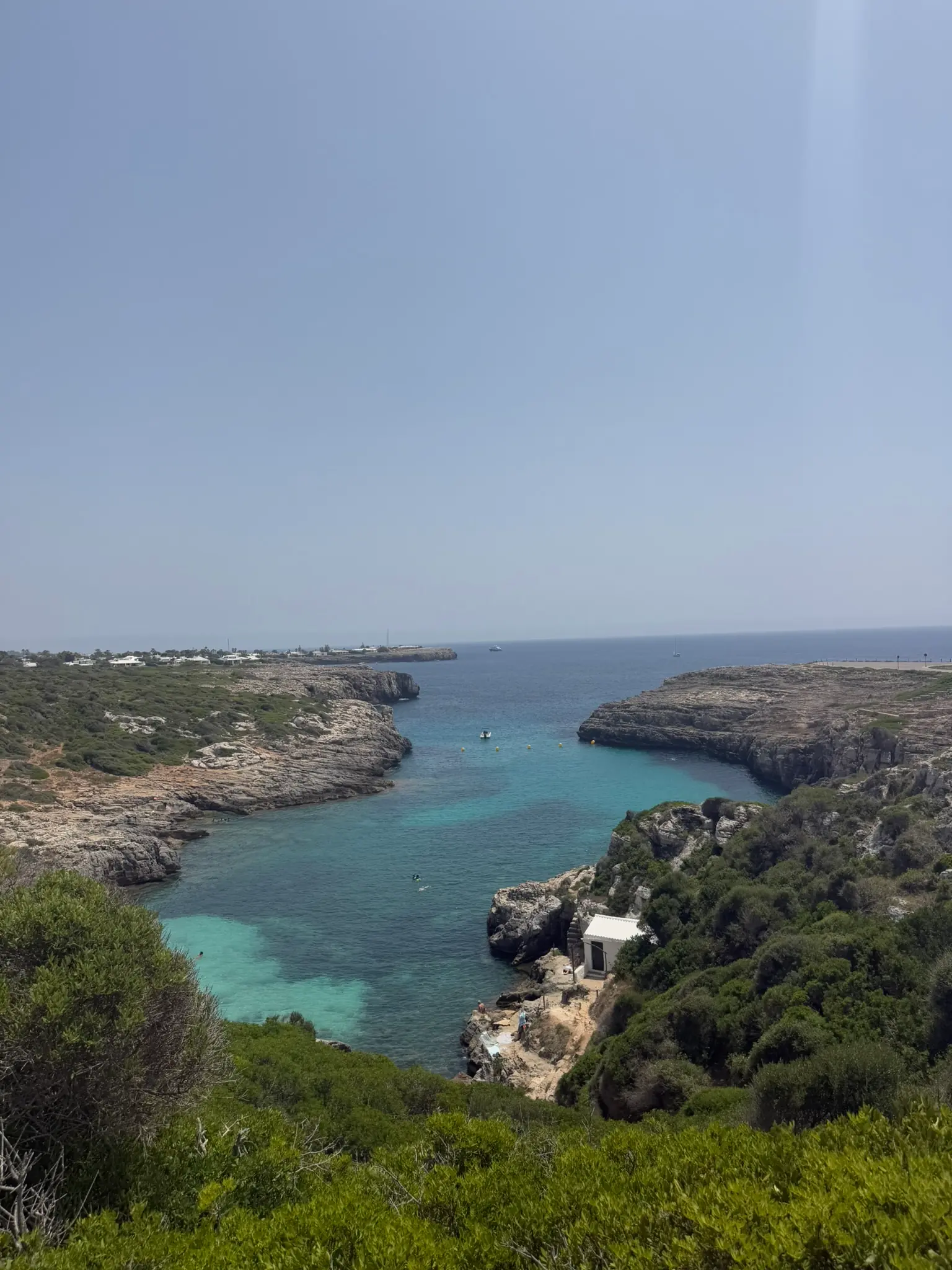 Luchtfoto langs Menorca's rotsachtige kustlijn, turquoise water grenzend aan bleke kalkstenen kliffen