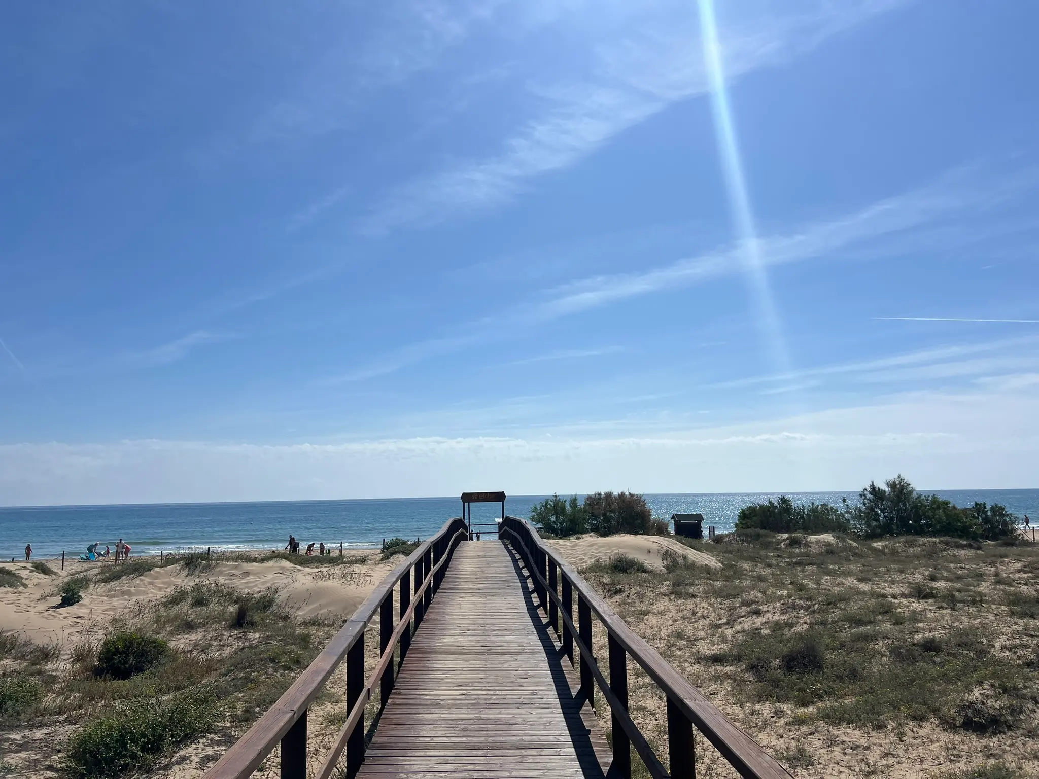 A scenic wooden boardwalk path leading directly to the golden sands and turquoise waters of Platja del Carabassí beach in Alicante, Spain.