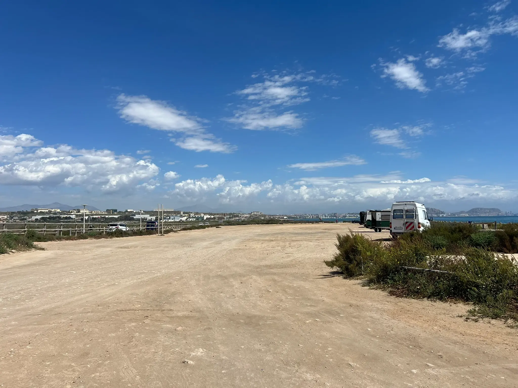 Playa del Saladar Alicante — large free sandy parking area near the beach with Alicante city views in background, campervan friendly